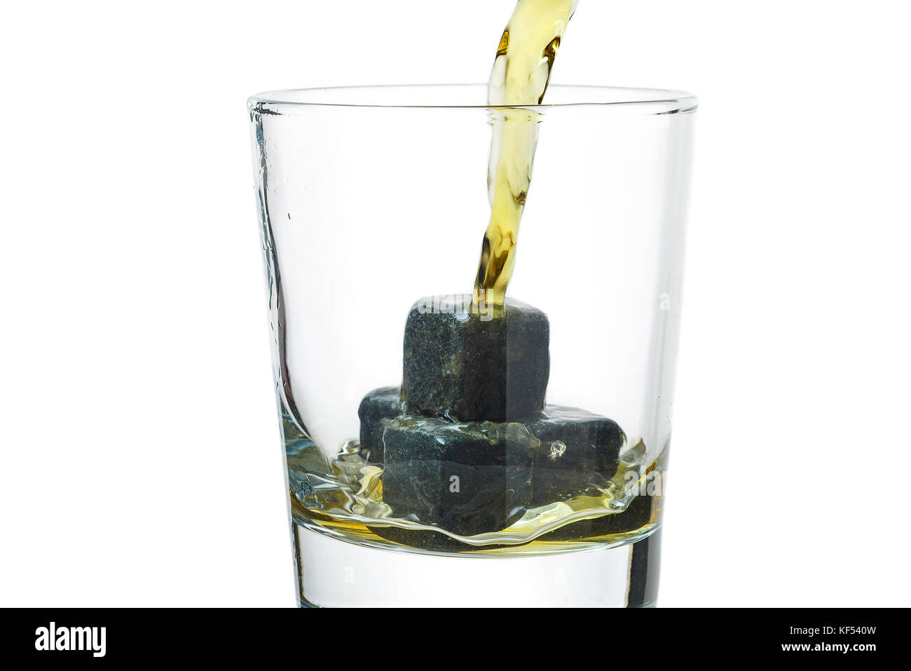 Whiskey gießt in ein Glas mit Steinen. Stockfoto