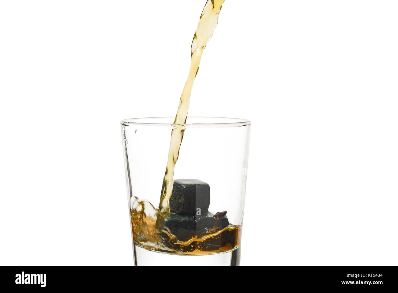 Whiskey gießt in ein Glas mit Steinen. Stockfoto