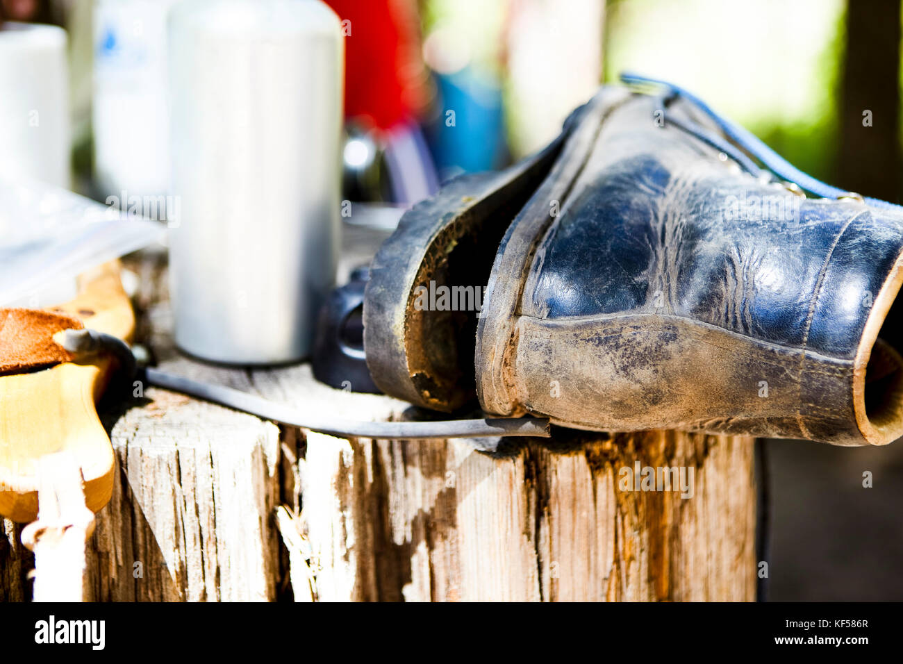 Alte leder Boot mit dem alleinigen lockert sich auf einem alten verwitterten Baumstamm im Freien in der Nähe zu sehen. Stockfoto