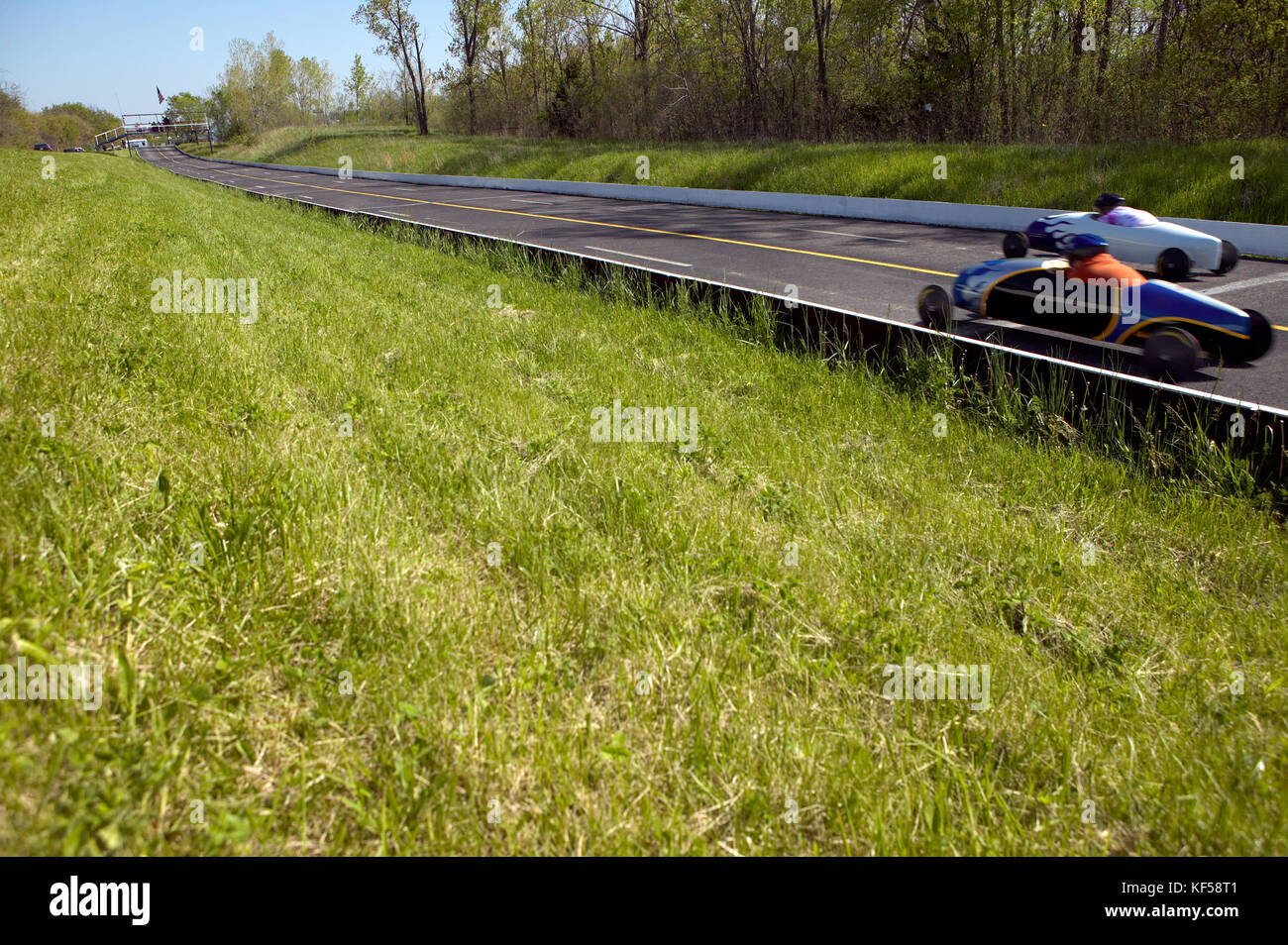 Zwei Autos konkurrieren in Geschwindigkeit Studien an einer amerikanischen Soap Box Derby für Fahrzeuge ohne eigene Stromversorgung durch Jugend angetrieben Stockfoto