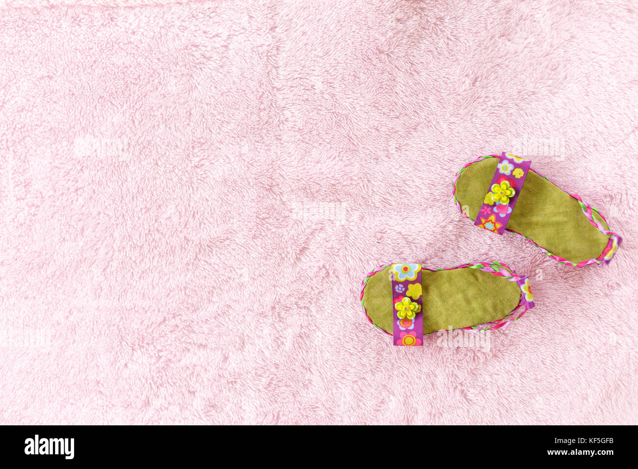 Paar lila Baby Mädchen Sandalen gegen eine blass rosa Hintergrund angeordnet Stockfoto