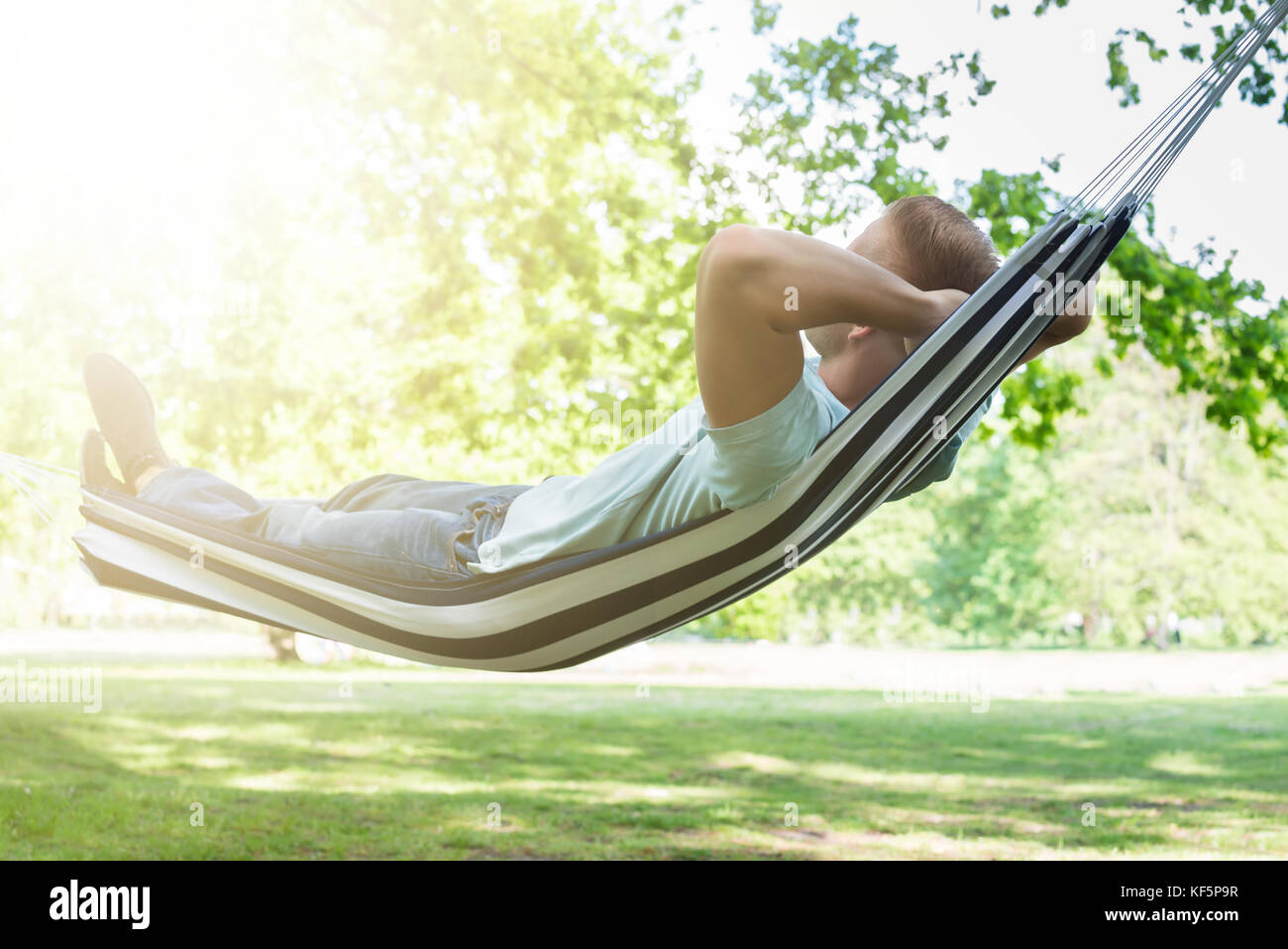 Junge Mann in der Hängematte entspannen im Park Stockfoto