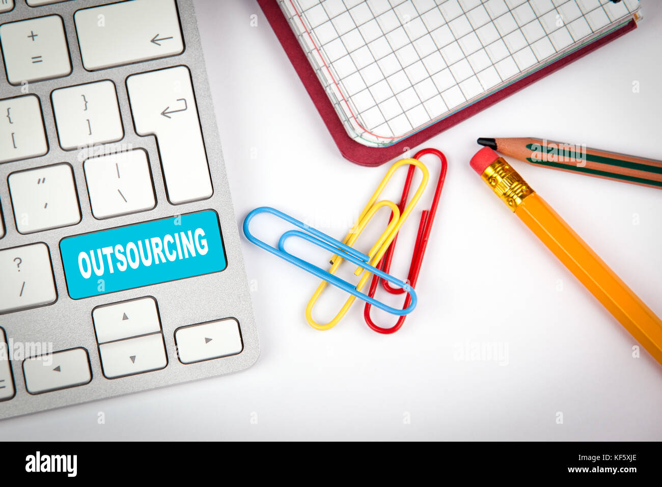 Outsourcing Konzept. Computer Tastatur auf einem weißen Büro Schreibtisch mit verschiedenen Gegenständen Stockfoto