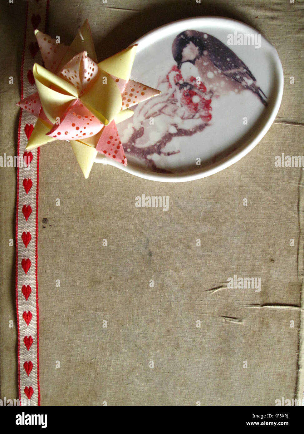 Weihnachten/Winter Dekoration mit Papier Stern, Vogel aus Keramik und Farbband auf altes Buch Textur Stockfoto