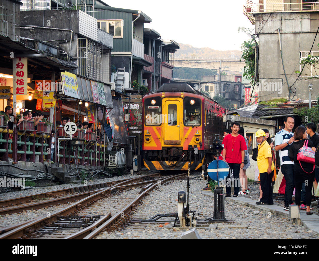 Der Zug fährt auf der Bahnstrecke entlang der Shifen Old Street in Richtung Shifen Station, wo viele Touristen auf der Seite, Pingxi District, Taiwan, zuschauen Stockfoto