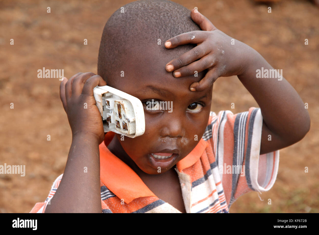 Leben im Slum in Kenia Aerias - Junge kid Spielen mit Handy ist beschädigt Stockfoto