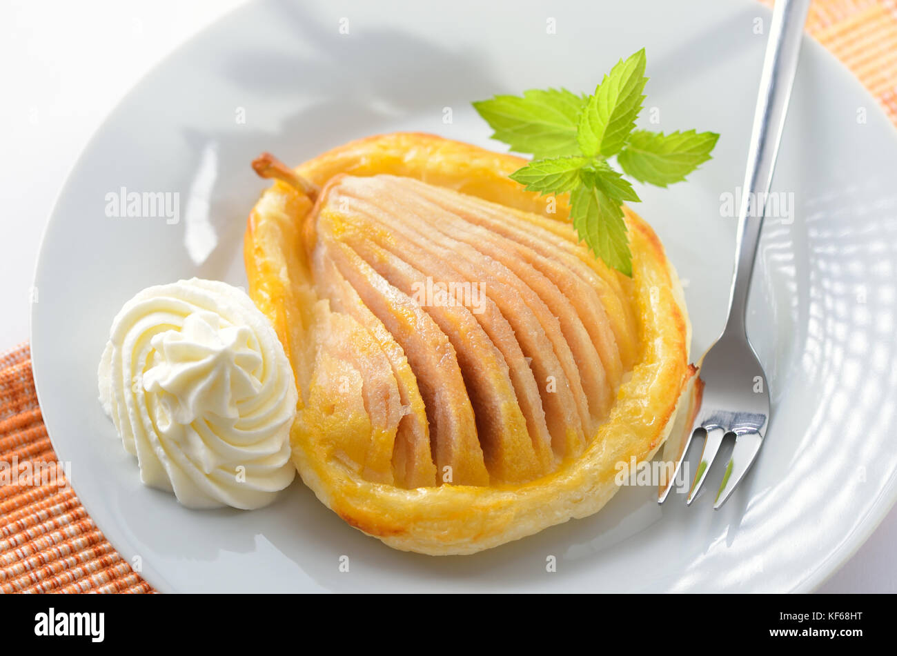 Birne mit Honig auf Blätterteig, serviert mit Sahne und Minze Stockfoto