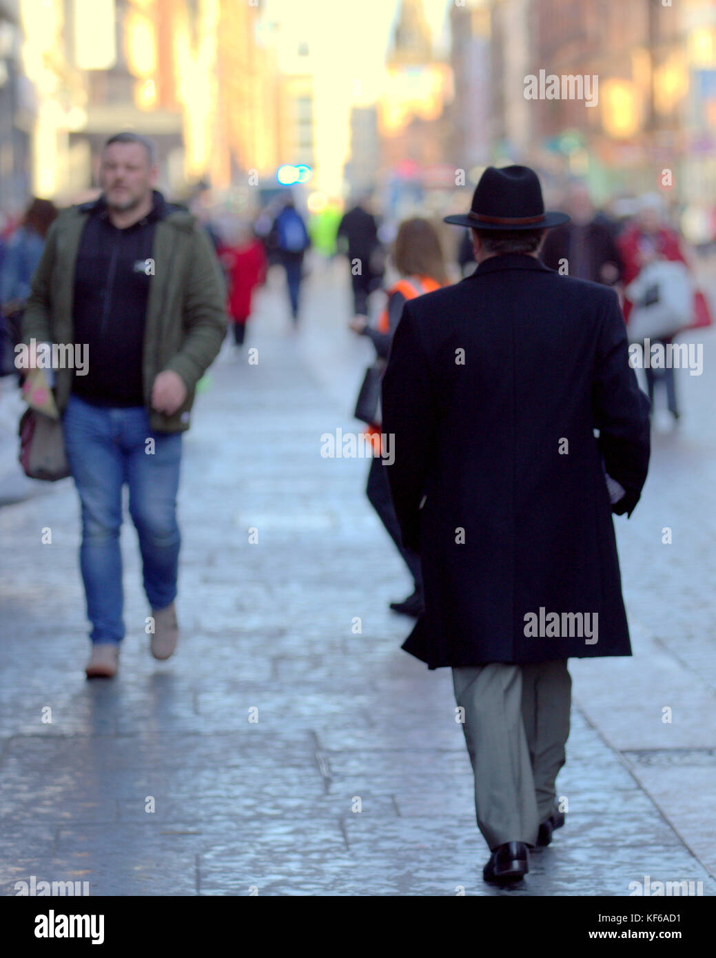 Gut gekleideter Mann mit Hut wandern aus gesehen hinter Glasgow Straße Gehweg Pflaster Stockfoto