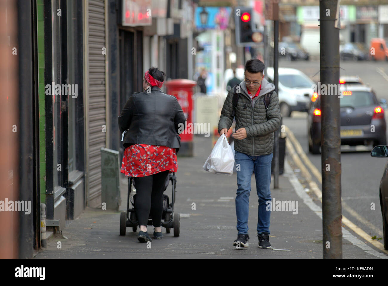 Große Frau schieben Kinderwagen Wandern aus gesehen hinter Glasgow Straße Gehweg Pflaster Stockfoto