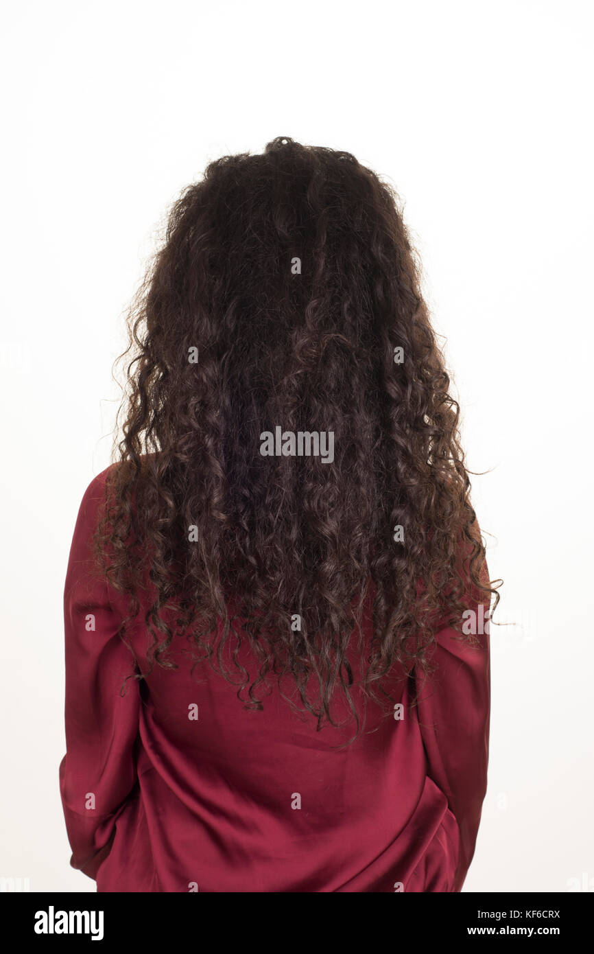 Ansicht der Rückseite eine junge Frau mit langen, lockigen dunkle Haare vor einem weißen Hintergrund stehen Stockfoto
