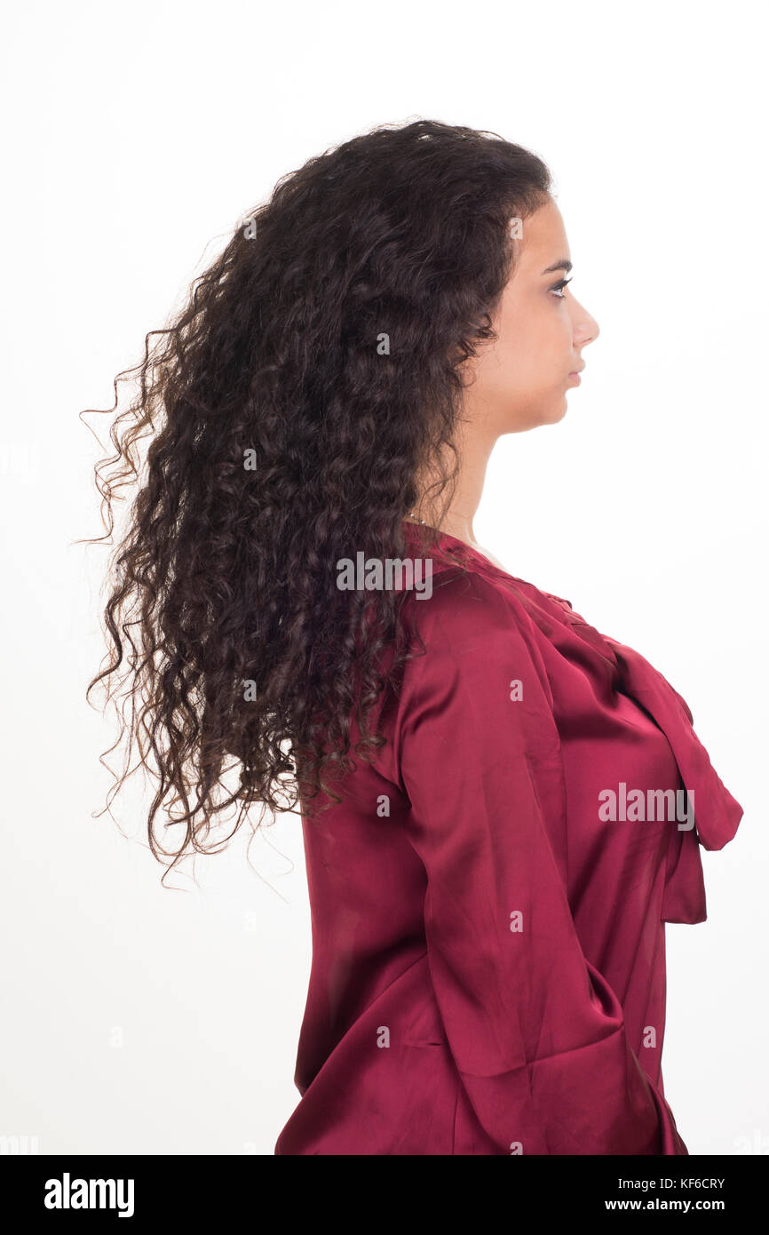 Seitenansicht Porträt einer jungen Frau mit langen, lockigen Haar vor einem weißen Hintergrund stehen Stockfoto