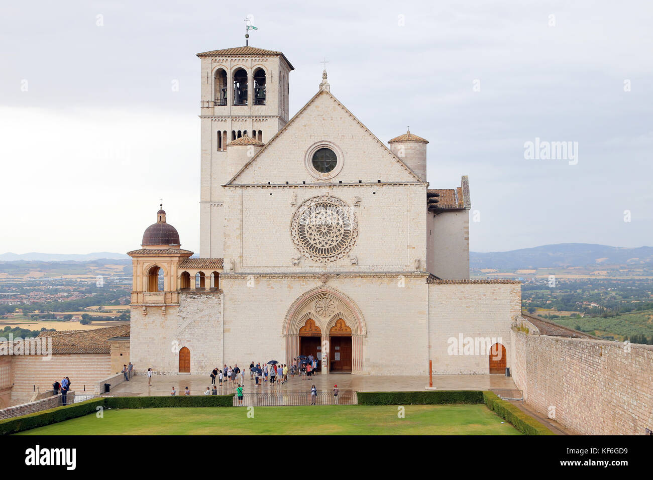ASSISI, ITALIEN 30. JUNI 2017: Berühmte Basilika des hl. Franz von Assisi (Basilica Papale di San Francesco) mit unterem Platz bei Sonnenuntergang in Assisi, Umbrien, Stockfoto