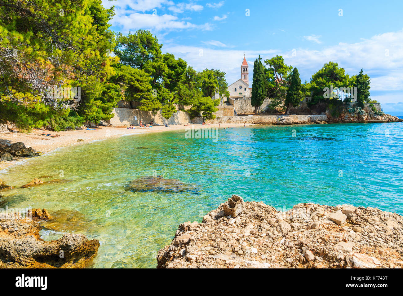 Strand mit smaragdgrünen Meer Wasser und Blick auf die Dominikanische Kloster in Abstand, Bol, Insel Brac, Kroatien Stockfoto
