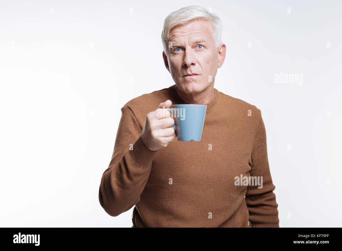 Älterer Mann mit Tasse Kaffee und runzelte die Stirn Stockfoto