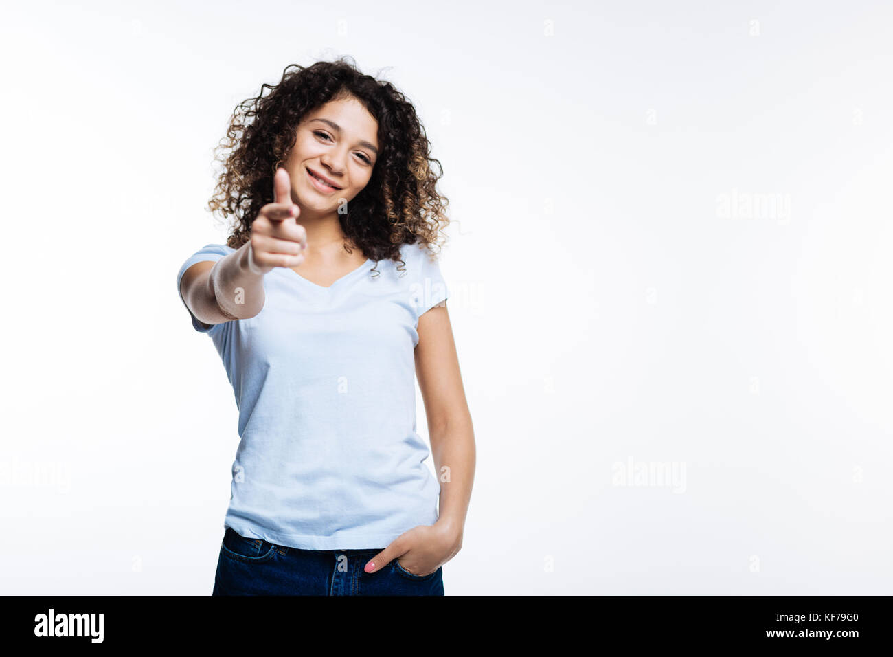 Fröhliche curly Frau an der Kamera zeigt mit Finger Stockfoto