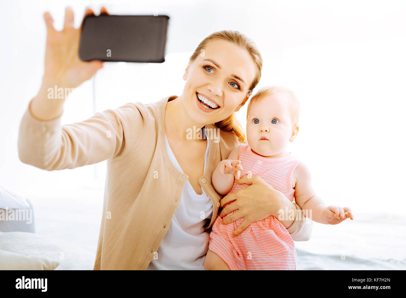 Lustige baby Suchen überrascht, während man ein Smartphone Stockfoto