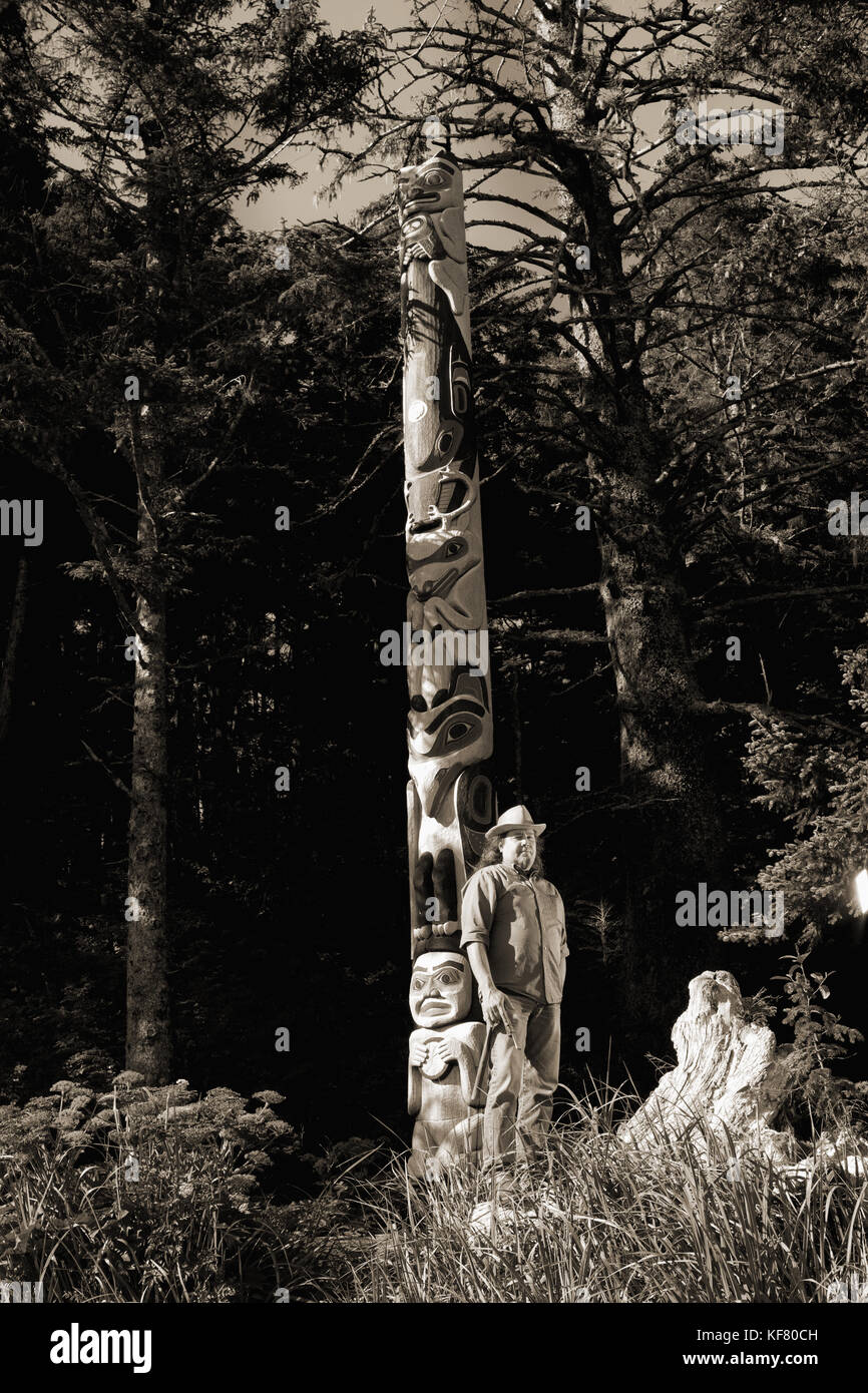 Usa, Alaska, Sitka, Tommy Joseph eine tinglit Totem Pole Carver vor einem seiner Schnitzereien, Halibut Cove, Sitka Sound steht Stockfoto