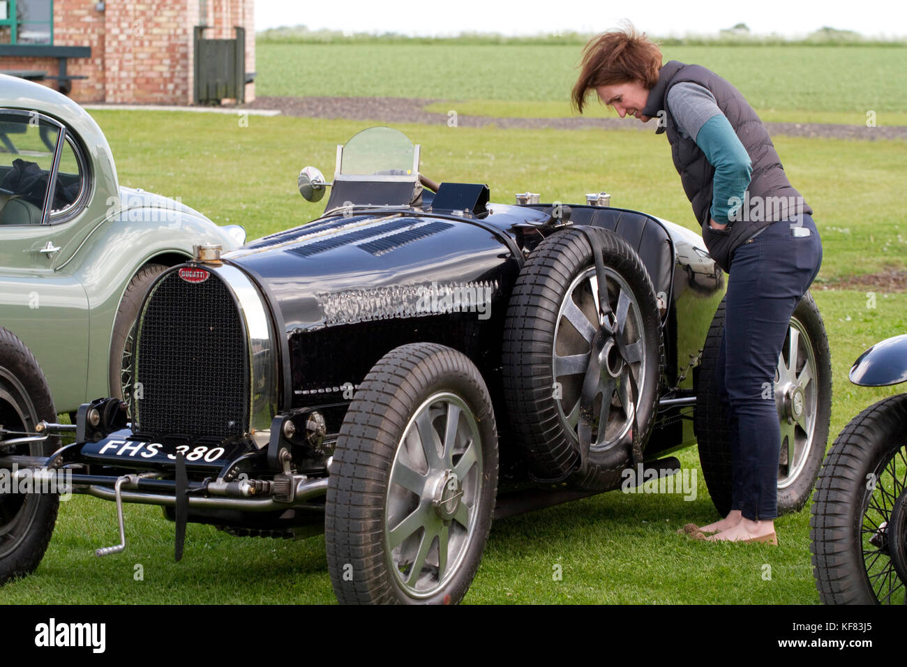 Frau, die einen klassischen Bugatti mit Softtop nach unten auf einem Besitzer-Club besucht, der das Parham Airfield Museum in Suffolk besucht Stockfoto