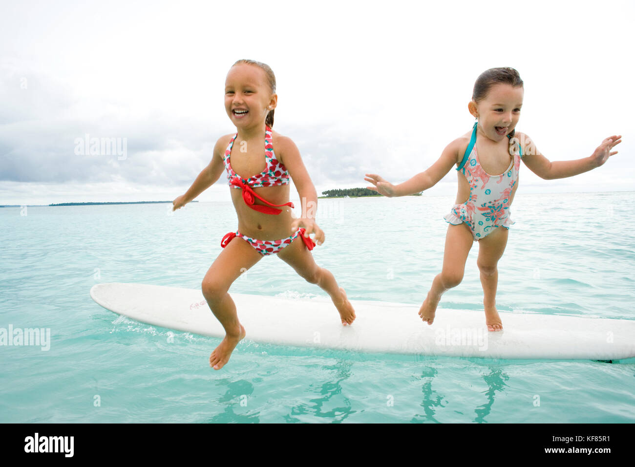 Indonesien, Mentawai Inseln, kandui Resort, Mädchen, Springen von einem Surfbrett in den Indischen Ozean Stockfoto