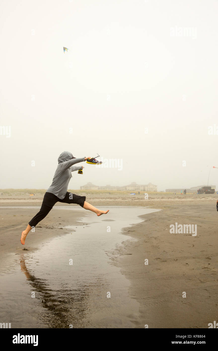 Usa, Washington State, Long Beach Halbinsel, international kite Festival, Frau springt über das Wasser zu trocken halten Stockfoto