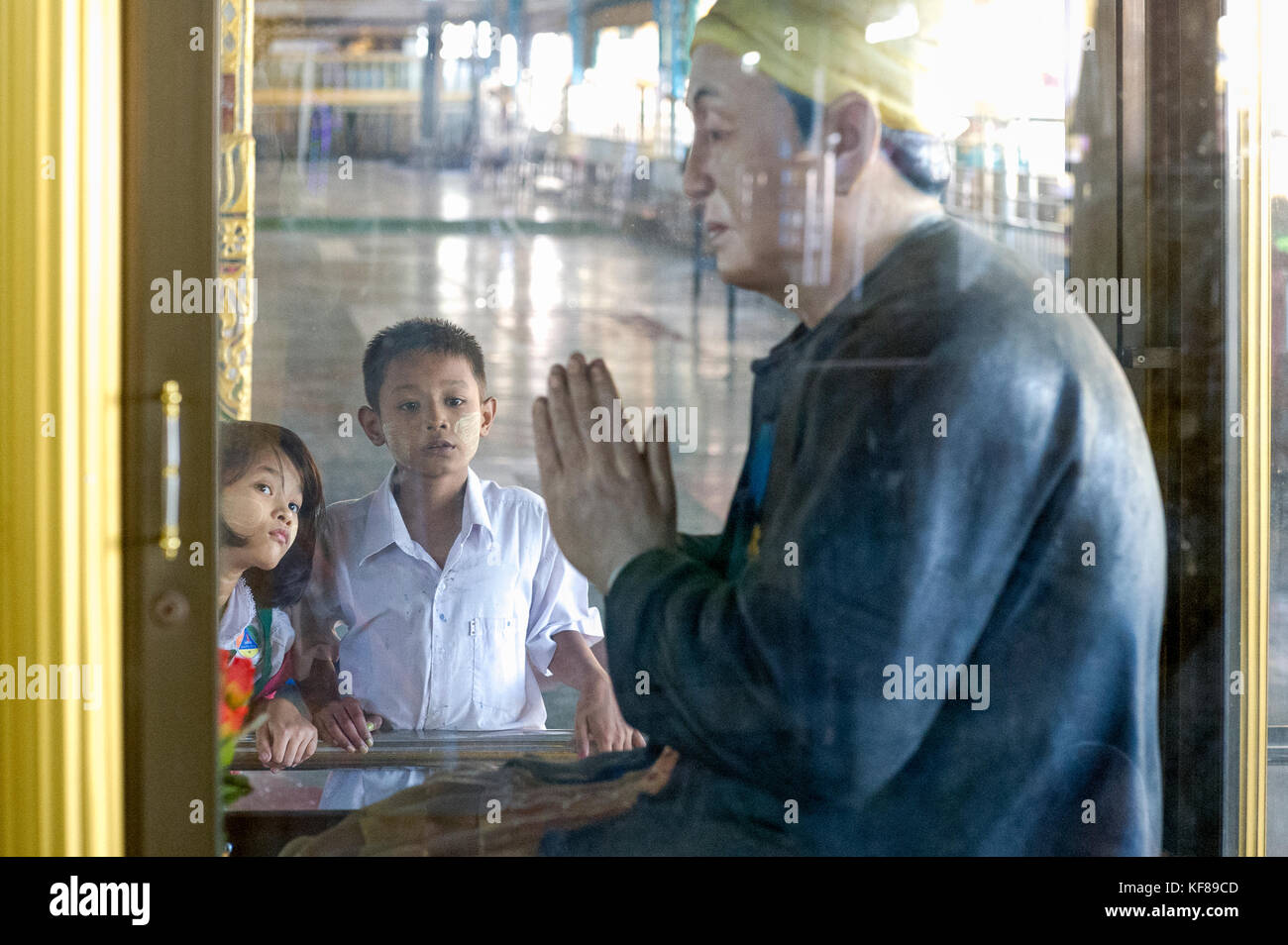 Myanmar (früher Birma). Yangon (Rangoon). Kyaukhtatgyi Pagode. Junge Kinder in der Bewunderung vor einer Statue Stockfoto