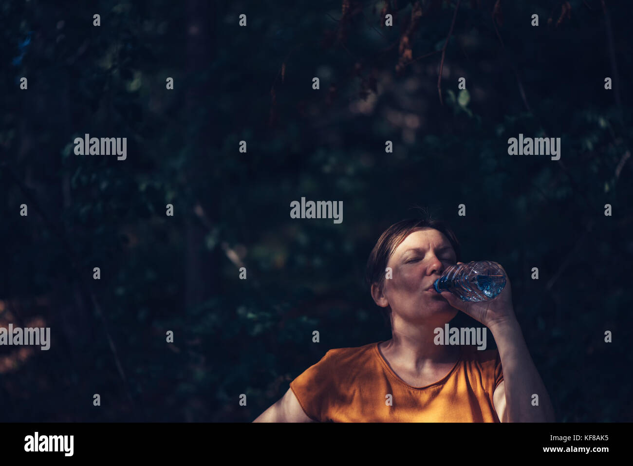 Frau trinkt Wasser draußen. durstig nach kaukasisch Weiblich erfrischend nach einem langen Spaziergang durch den Park auf sonnigen Sommertag, ungewöhnliche Framing, selektive Stockfoto