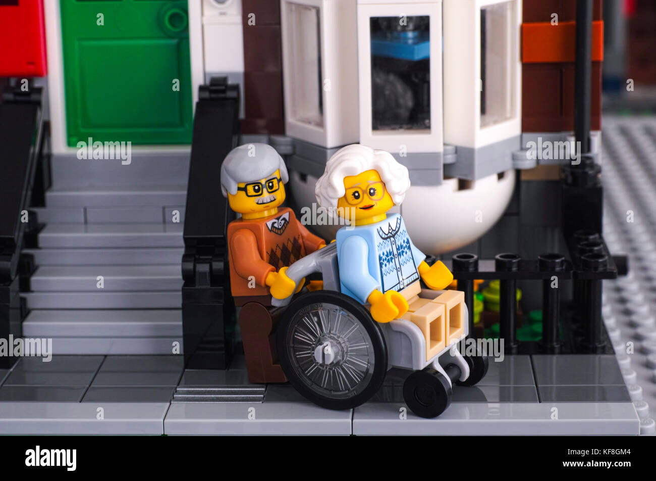 Tambow, Russische Föderation - Oktober 18, 2017 Lego senior Paar in der Nähe von seinem Haus in der Straße. Frau Sitzen im Rollstuhl, ihrem Mann helfen. Studio gedreht. Stockfoto