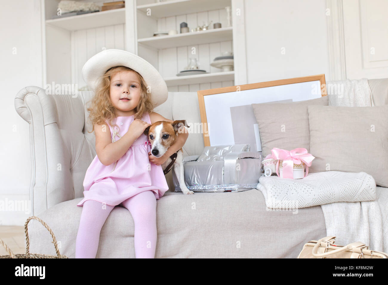 Charming Girl posiert mit Hund auf Sofa im Innenbereich Stockfoto