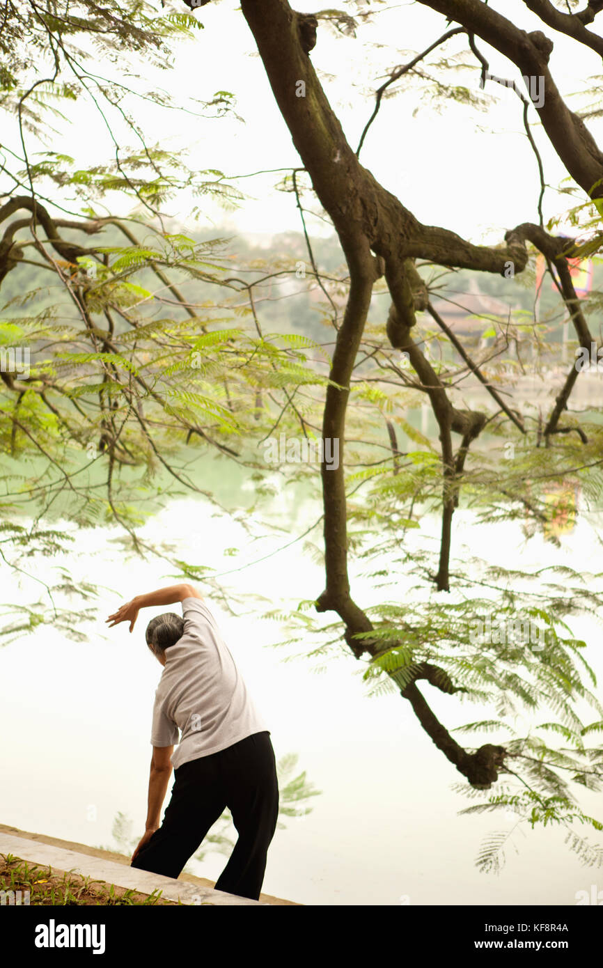 Vietnam, Hanoi, eine Frau führt tai Chi und erstreckt sich am frühen Morgen den Hoan Kiem See Stockfoto