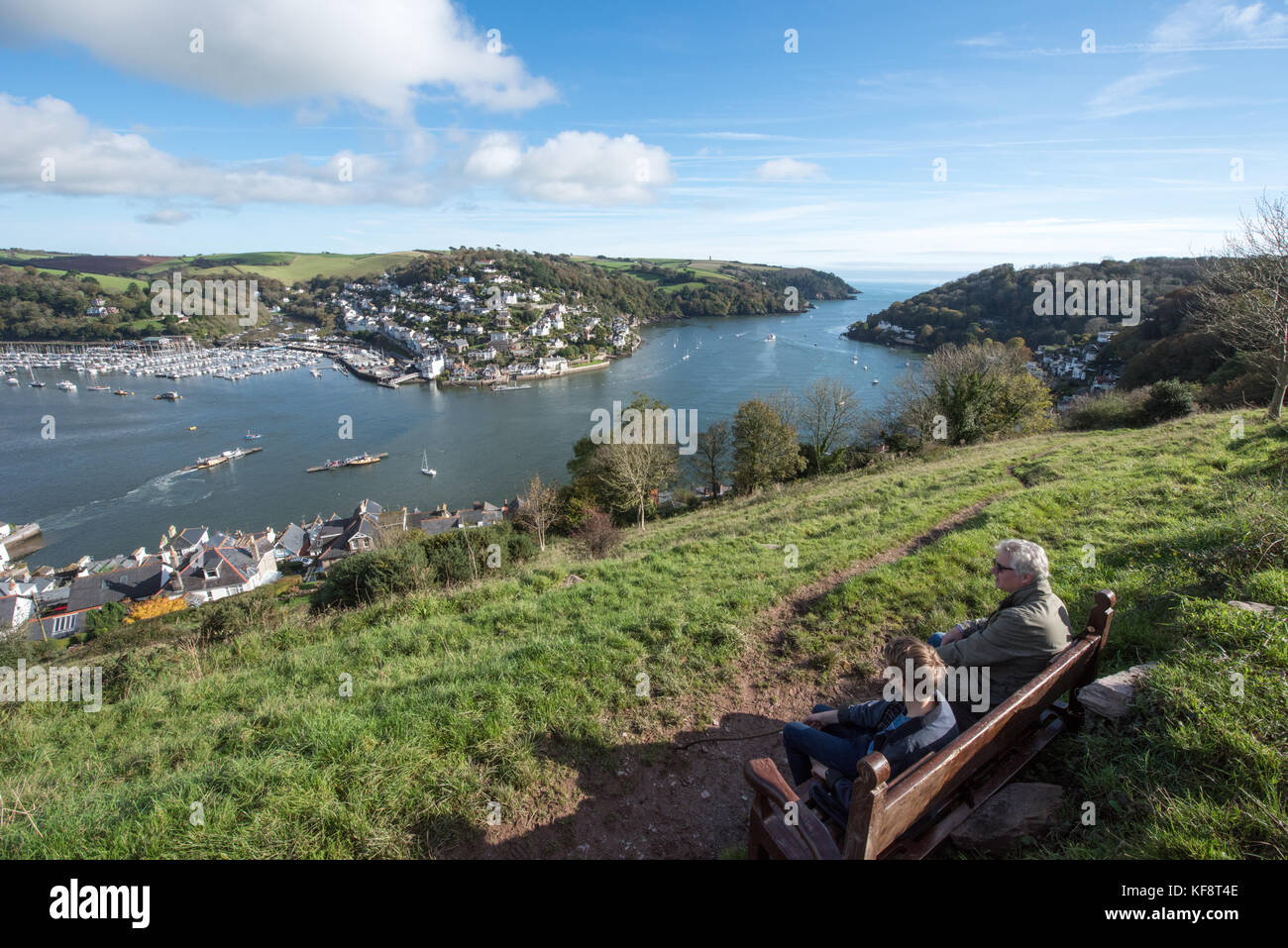 Blick auf den Fluss Dart mit Blick auf das Meer und Kingswear von Bateman's Hill mit zwei Personen auf einem Bank genießen die spektakuläre Aussicht Stockfoto