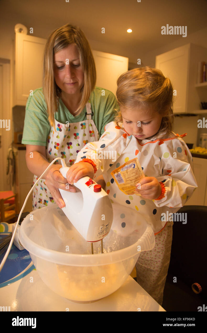 Mutter und Tochter das Mischen von Zutaten in der Vorbereitung für das Backen eines Kuchens Stockfoto