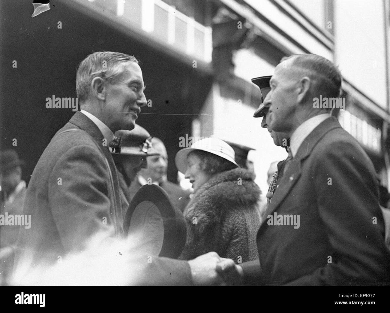 Dieses historische Foto zeigt den Abschied eines Gouverneurs, wahrscheinlich aus einer ehemaligen britischen Kolonie oder einem ehemaligen britischen Territorium, an einem Kai. Der Gouverneur wird von einem VIP verabschiedet, was die Wichtigkeit ihrer Abreise verdeutlicht. Stockfoto Dieses historische Foto zeigt den Abschied eines Gouverneurs, wahrscheinlich aus einer ehemaligen britischen Kolonie oder einem ehemaligen britischen Territorium, an einem Kai. Der Gouverneur wird von einem VIP verabschiedet, was die Wichtigkeit ihrer Abreise verdeutlicht. Stockfoto