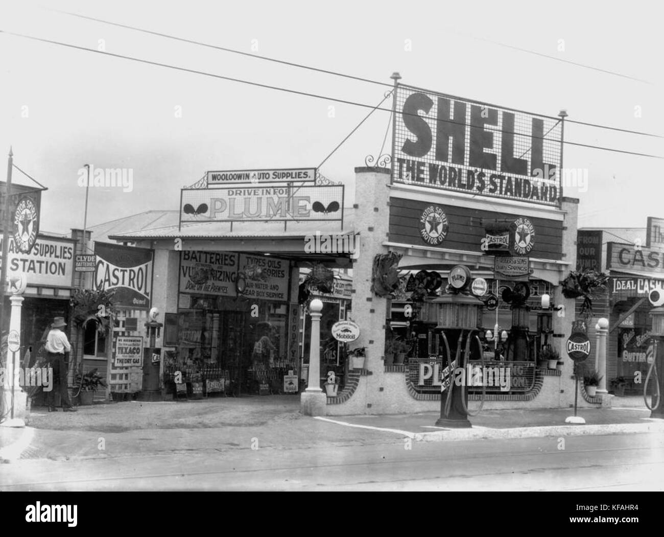 Dieses historische Bild aus der Zeit um 1935 zeigt einen Autoverkehr bei Wooloowin Auto Supplies, bei dem Kunden ihre Autos mit Shell-Benzin befüllen oder Plume-Produkte kaufen konnten. Sie spiegelt den wachsenden Trend der Automobildienstleistungen zu Beginn des 20. Jahrhunderts wider. Stockfoto