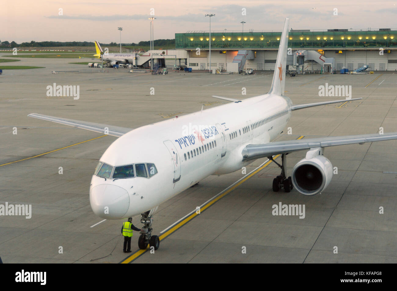 Mann mit einem gelben-viz Waffenrock durch das bugrad Fahrwerk eines Israir Boeing757-200 ER geparkt mit Germanwings Airbus A 319 auf dem geparkt Stockfoto