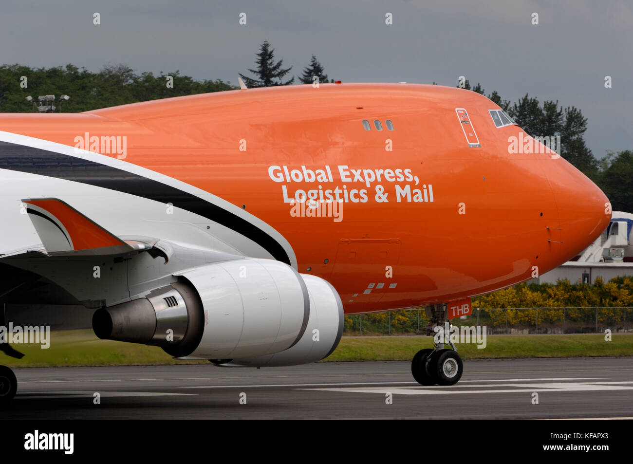 Winglet, Motoren und Nase von einem TNT Airways Boeing 747-400 mit Global Express, Logistics & Mail und Bäume hinter Stockfoto