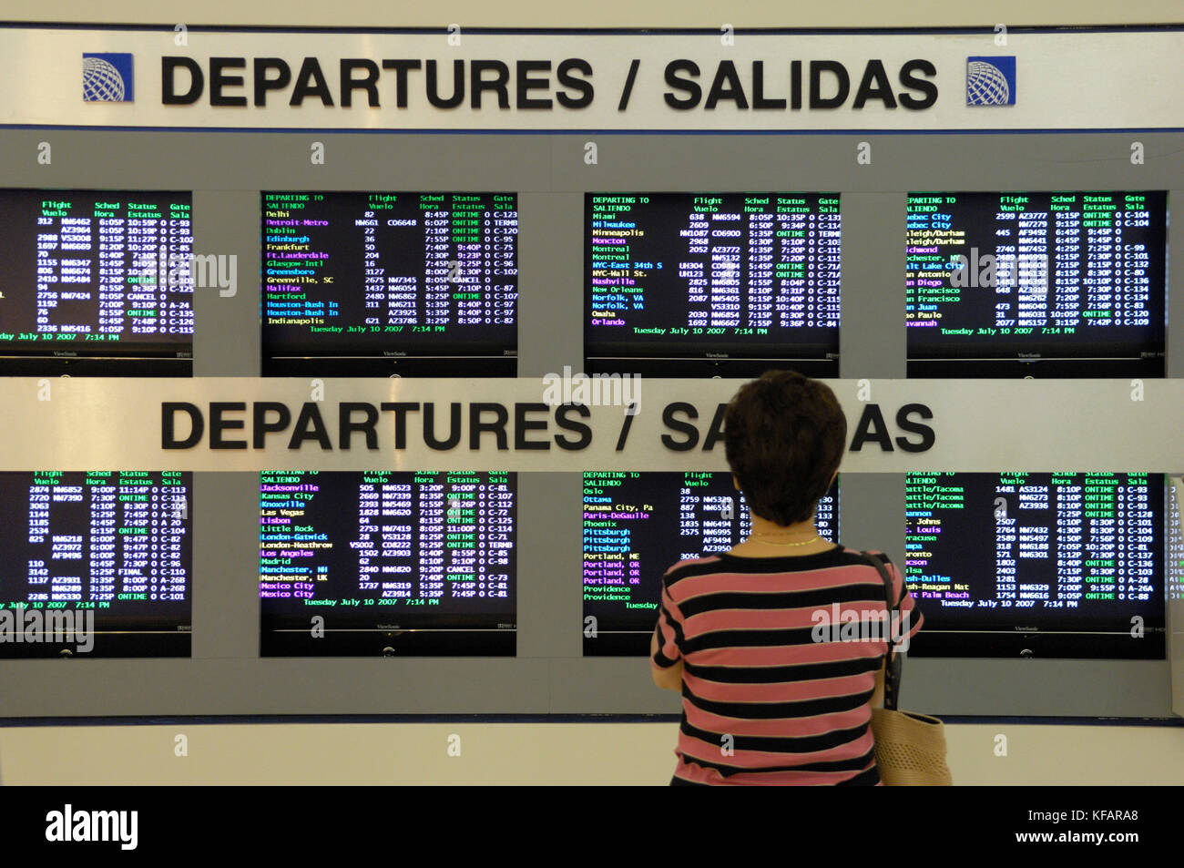 Eine Frau Passagier an der Abflüge Informationen Bilder Suchen mit Zeichen in englischer und spanischer Sprache in der TerminalC Stockfoto