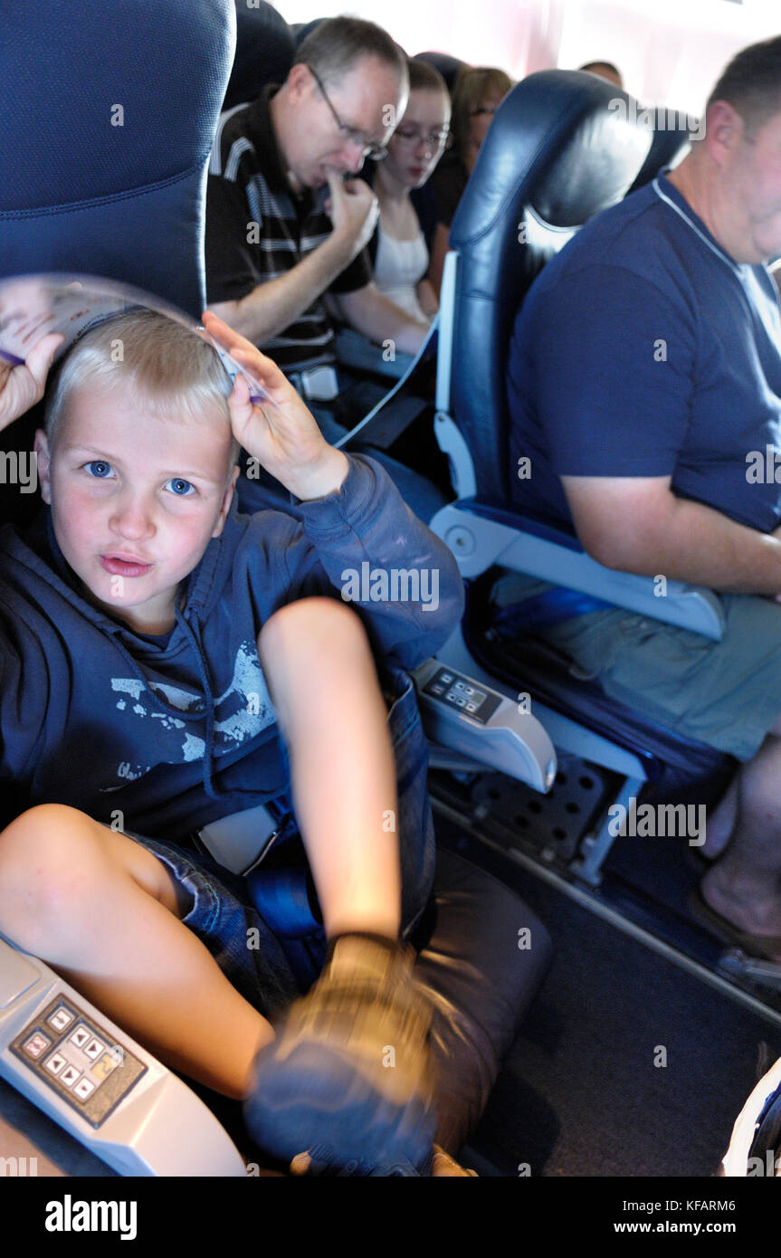 Henry Sitzen mit dem Safety-card, Mann und Frau lesen Zeitschriften hinter in der Economy-class Sitze hinter auf einem thomsonfly.com Boeing 767-300 Stockfoto