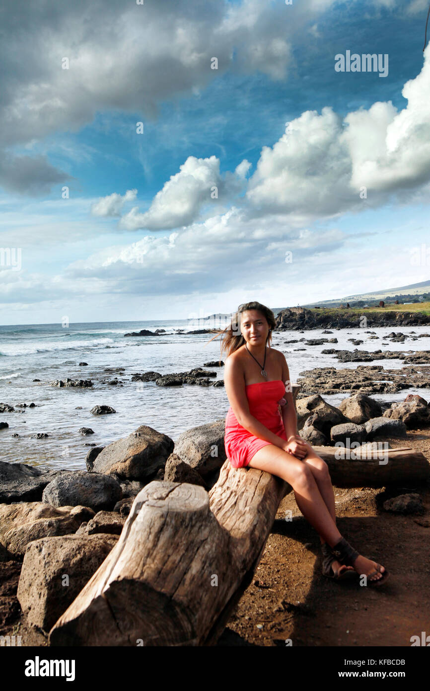 Easter Island, Chile, Isla de Pascua, Rapa Nui, eine Frau auf einem Baumstamm in der Nähe der Küste in der Nähe von Hanga Roa sitzt Stockfoto