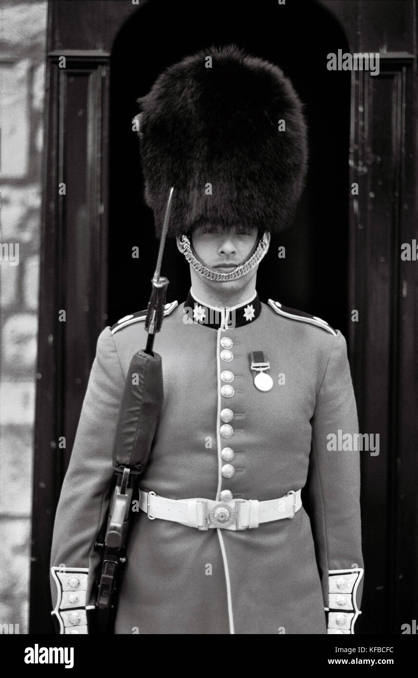ENGLAND, London, eine britische Royal Guard steht zu Fuß auf dem Vorplatz des Buckingham Palace (B&W) Stockfoto
