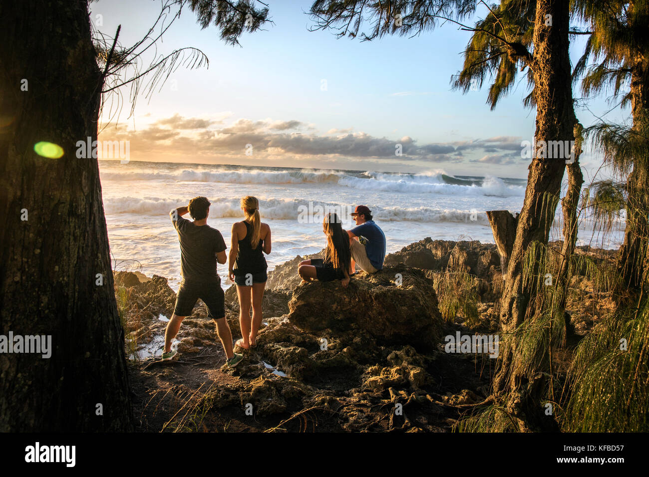 Hawaii, Oahu, North Shore, Umstehende sehen Sie eine große Rolle in Schwellen bei Sonnenuntergang an pupukea Beach Park an der Nordküste Stockfoto