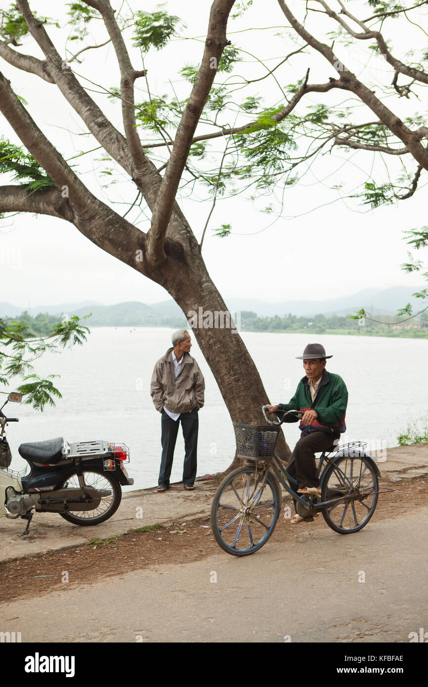 Vietnam, Hue, ein Mann fährt mit dem Fahrrad neben dem Perfume River Stockfoto