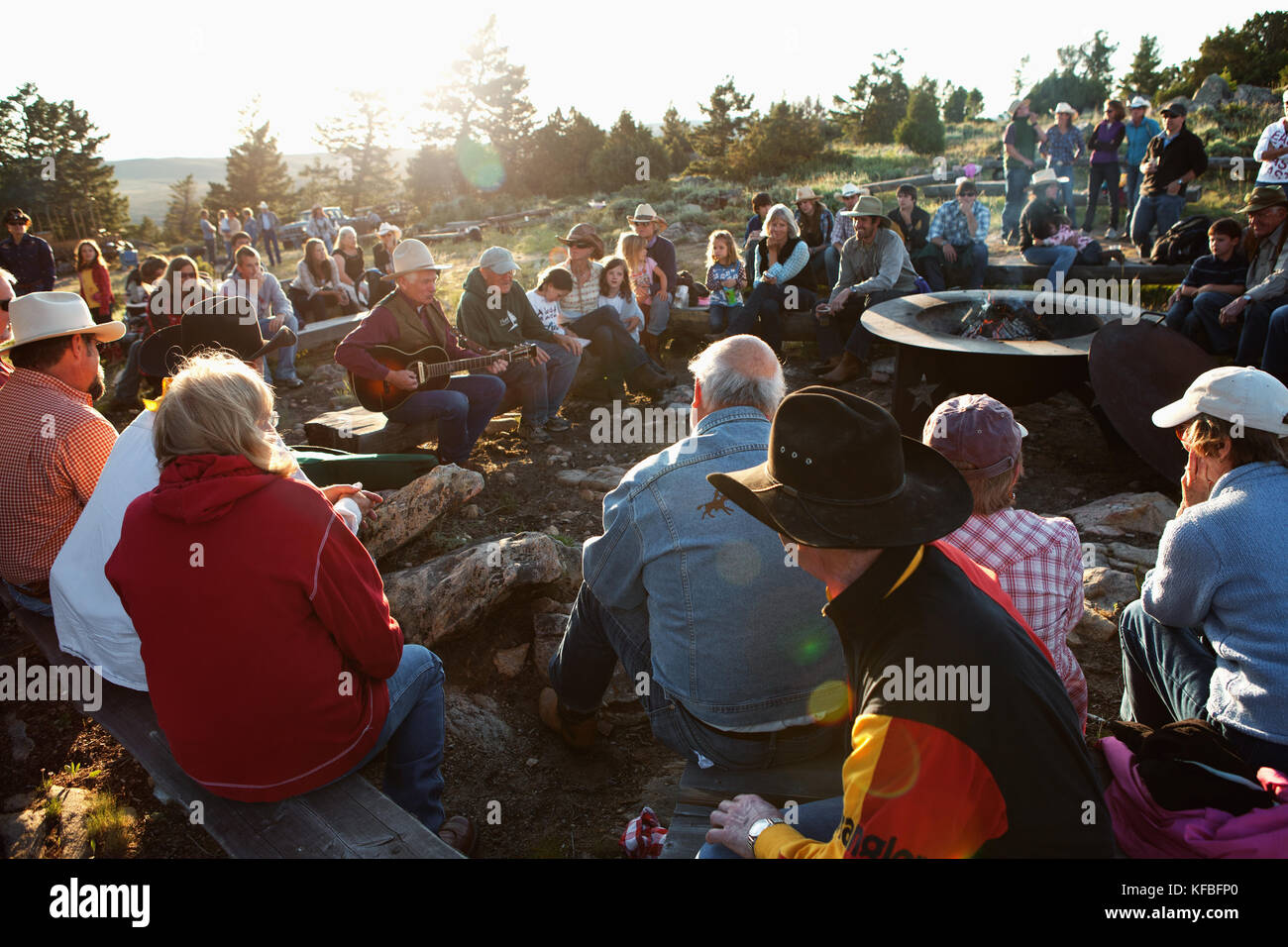 Usa, Wyoming, Lager, Gäste an einem Dude Ranch Sitzen am Lagerfeuer und ein Mann Gitarre spielen hören und singen Country Western songs, abara Ranch Stockfoto