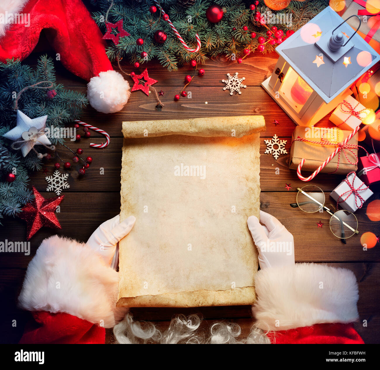 Santa claus Schreibtisch lesen Wunschliste mit Ornament und Weihnachtsgeschenk Stockfoto