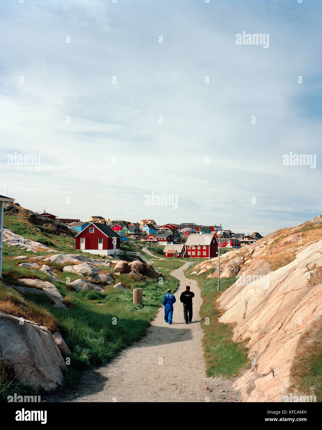 Grönland, Ilulissat, Rückansicht der Männer gehen auf Weg mit Häusern im Hintergrund Stockfoto