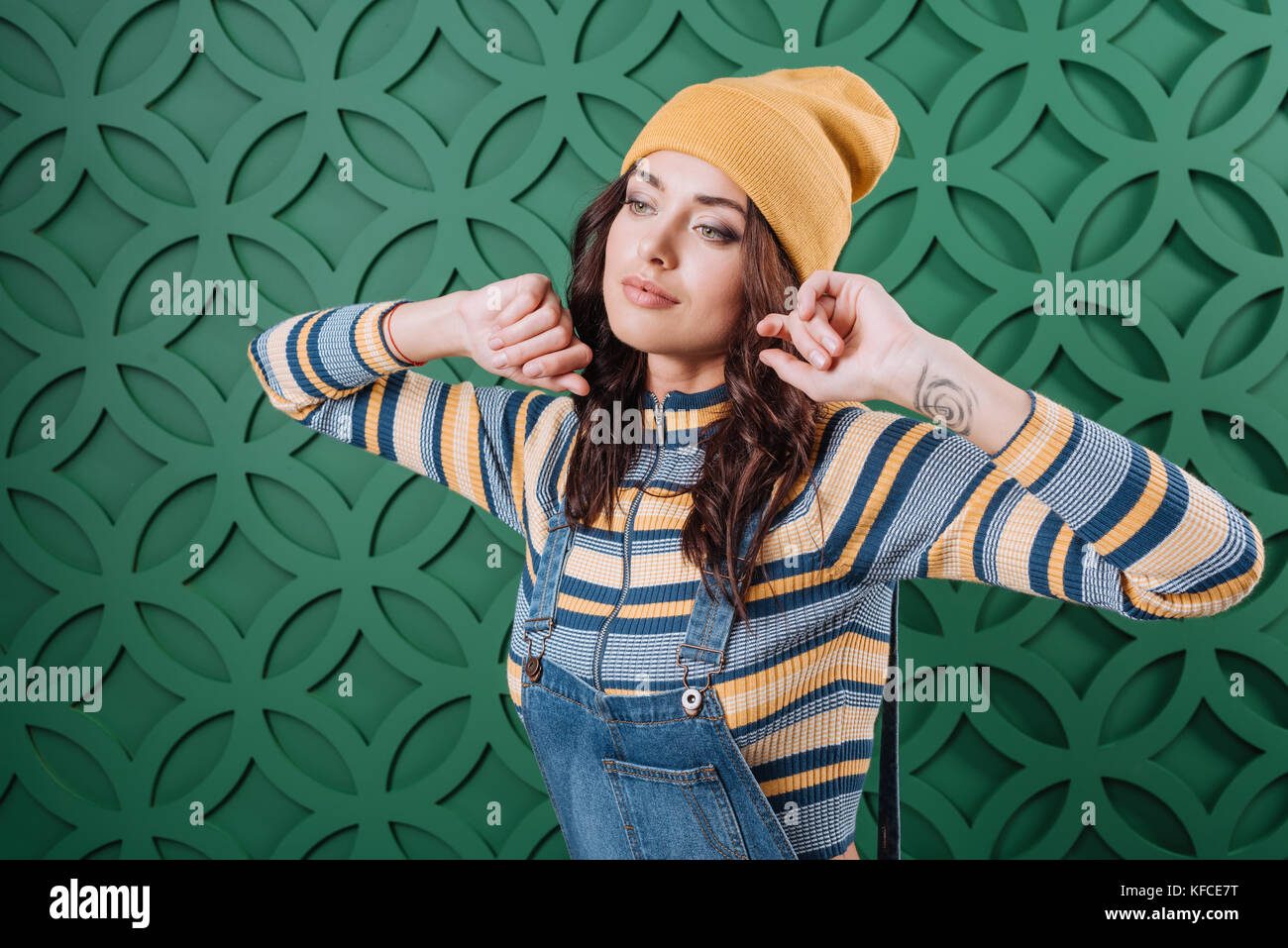 Frau in Pullover, Hut und Overalls posing Stockfoto