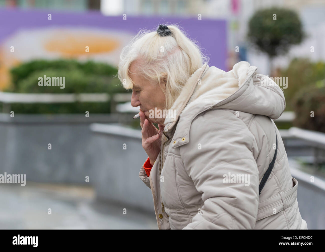 Ältere kaukasische Frau, die draußen in Großbritannien eine Zigarette raucht. Stockfoto