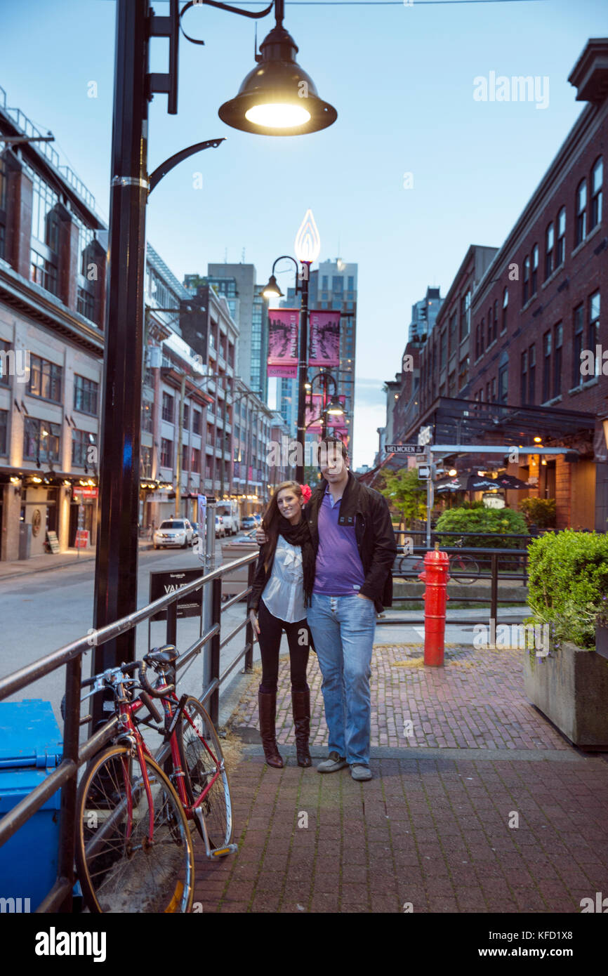 Kanada, Vancouver, British Columbia, ein Paar steht auf der Straße in der Dämmerung in der Nähe des blauen Wasser Cafe und Raw Bar in yaletown Stockfoto
