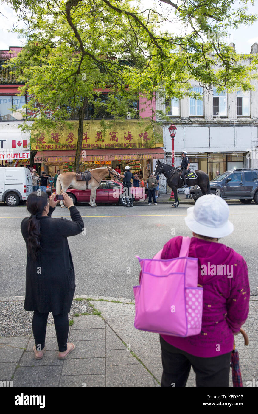 Kanada, Vancouver, British Columbia, die Damen machen Sie Fotos von der Royal Canadian Mounted Police stoppen ein Mann in seinem Auto in China Town. Stockfoto