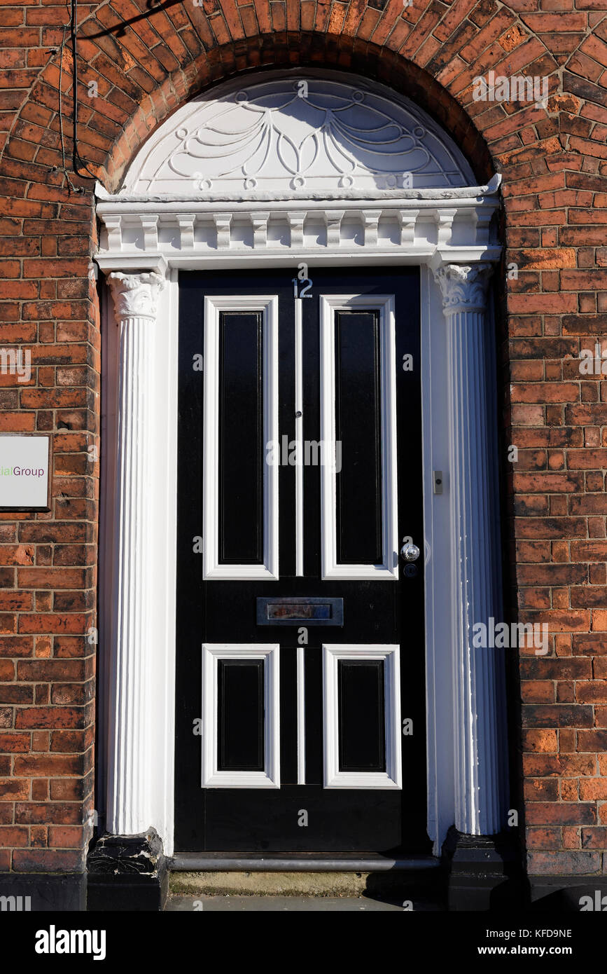 Verzierte weiße Türeinfassung mit geriffelten Pilastern und schwarz-weißer Viertäfeltür aus Holz St marys Place in Bury lancashire uk Stockfoto