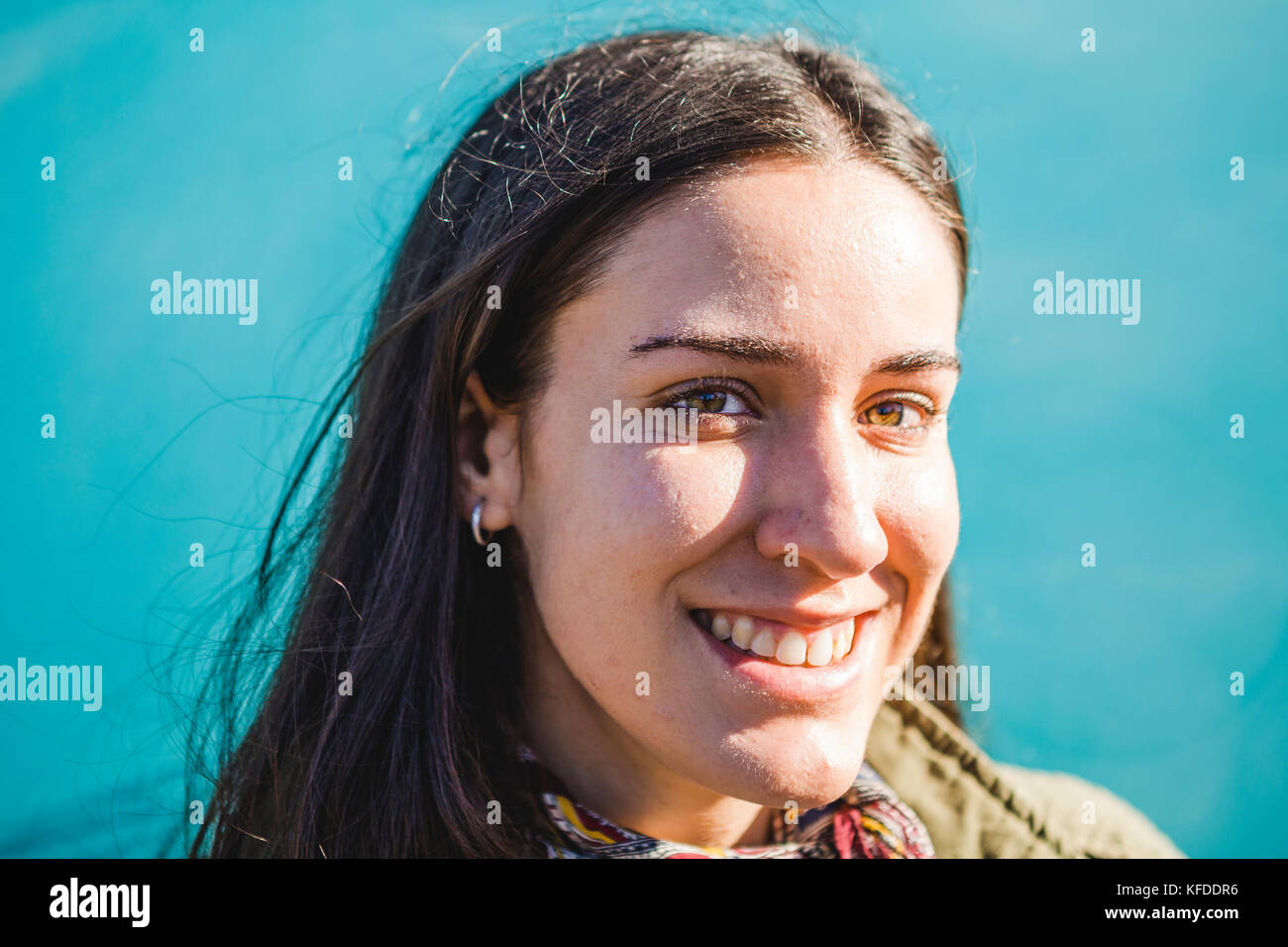Porträt einer jungen Brünette Frau lächelt vor einem blauen Hintergrund Stockfoto